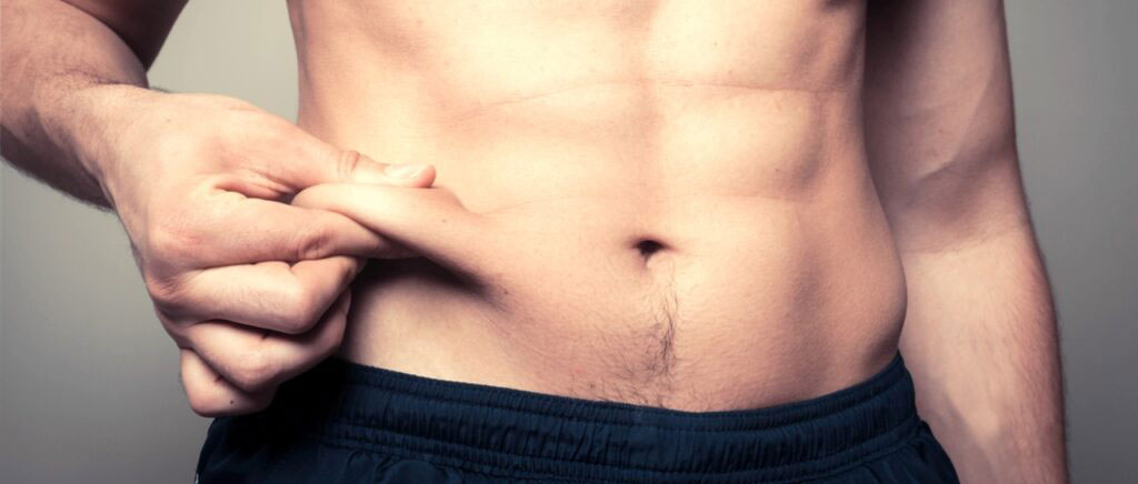Fit young man pinching his stomach