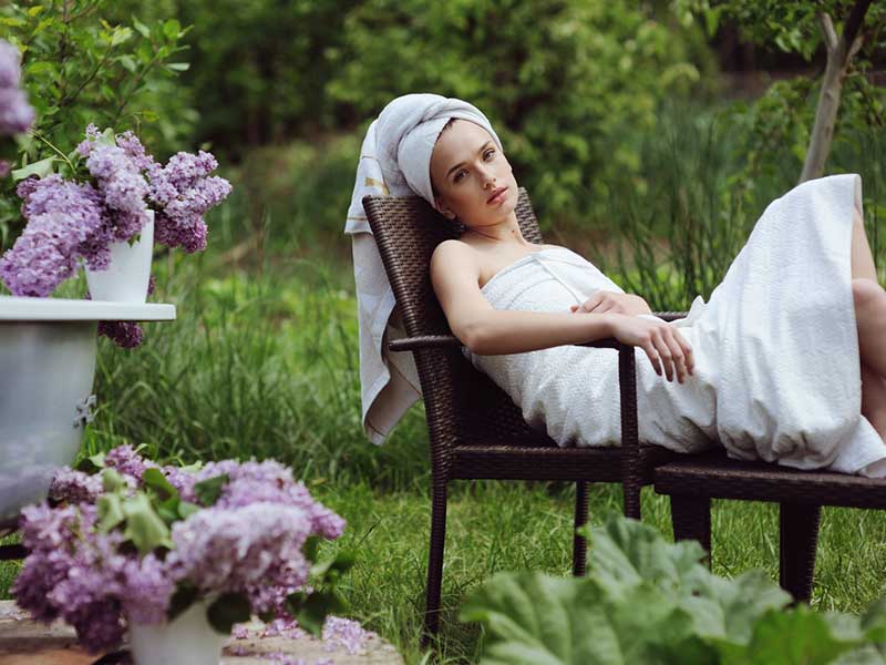 A women wearing a bathrobe and relaxing on a chair outside