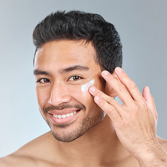 smiling man with his hand applying facial treatment